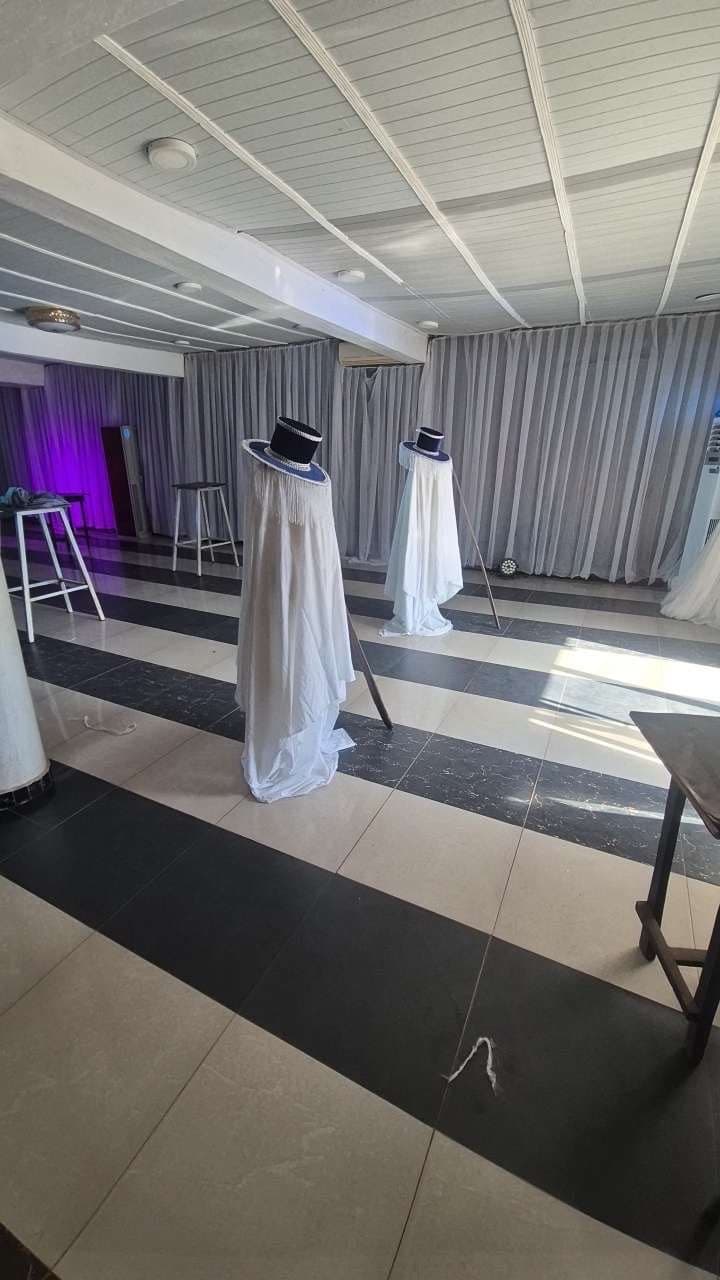 Venue being styled with white drapes and costume pieces